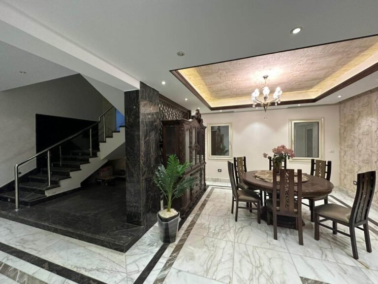 تشطيب فيلا راقية في مصر من تنفيذ بيت تايكون، يظهر ريسبشن واسع بأرضيات رخام وسلم داخلي فخم وأسقف معلقة.