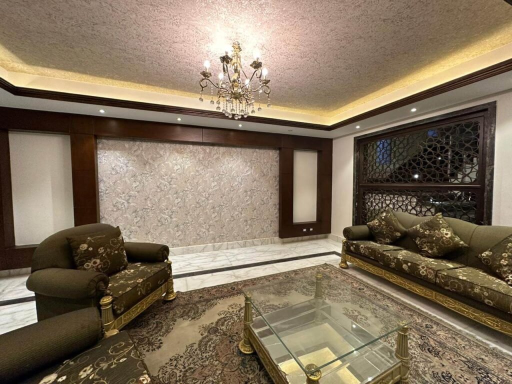 تشطيب غرفة معيشة في فيلا مع مكتبة تلفزيون من الخشب وتصميم يوفر الراحة والدفء للعائلة